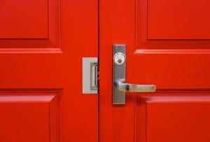 Close up of red door with handle and electric strike