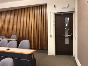 bronze exit device on wood door in lecture hall